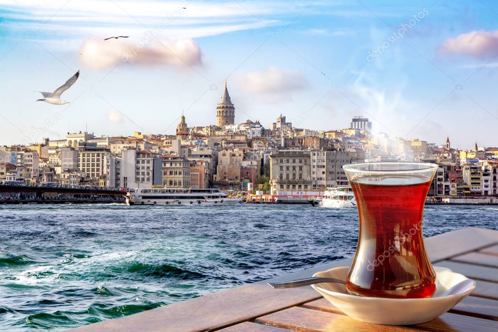 A cup of Turkish tea in a traditional glass against the background of the Golden Horn and the Galata Tower in Istanbul