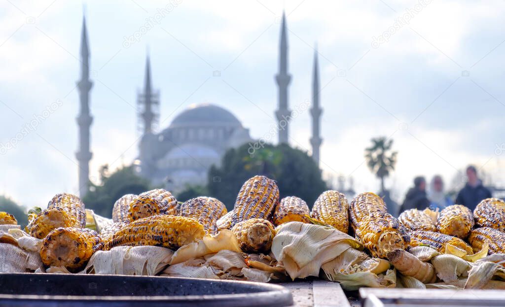 Baked corn on a street vendor cart in the historical center of Istanbul, Turkey with a blue mosque in the background