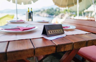 Plaj tatil köyündeki bir restoranda rezervasyonu olan masa servisi.