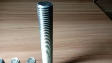 somun ve cıvata görüntüleri ahşap masada.