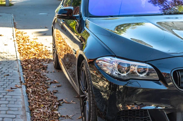 Oscuro coche deportivo se encuentra en la carretera en otoño día soleado primer plano — Foto de Stock