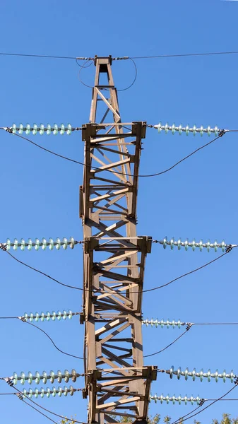 Mavi gökyüzünde bir arka planda yüksek voltaj hattı, mast ve teller — Stok fotoğraf