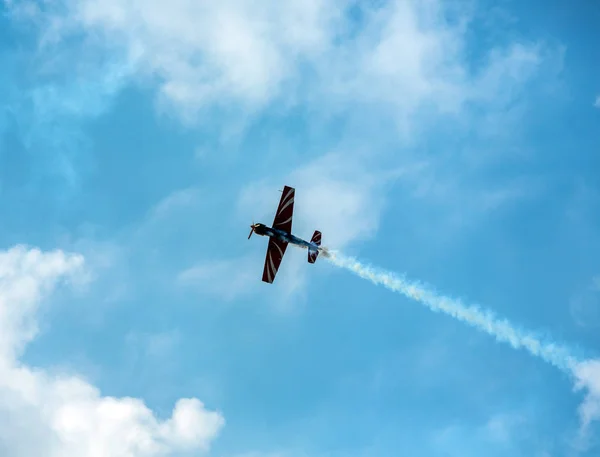 Silhouette sport aircraft with propellers, performing tricks with a smokescreen against the blue sky in the air show performance