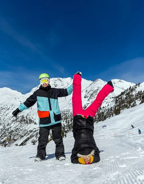 Happy funny couple on the background of snowy mountains. Standing upside down and showing OK sign