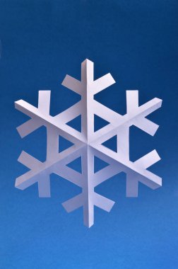 Kağıt kar tanesi tatil projeler veya kar yayınlar için koyu mavi arka planda.