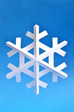 Kağıt kar tanesi tatil projeler veya kar yayınlar için mavi arka planda.