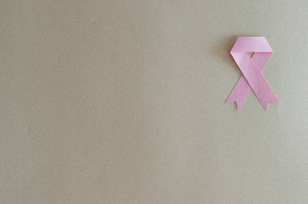 Breast cancer ribbon made from paper with beige background.