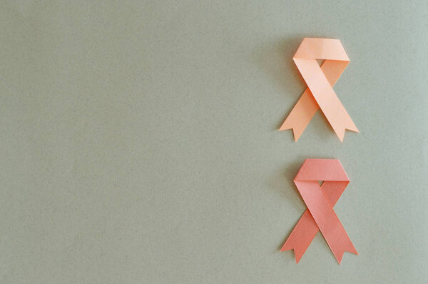 Duo of leukemia and uterus cancer ribbon made with paper on beige background.