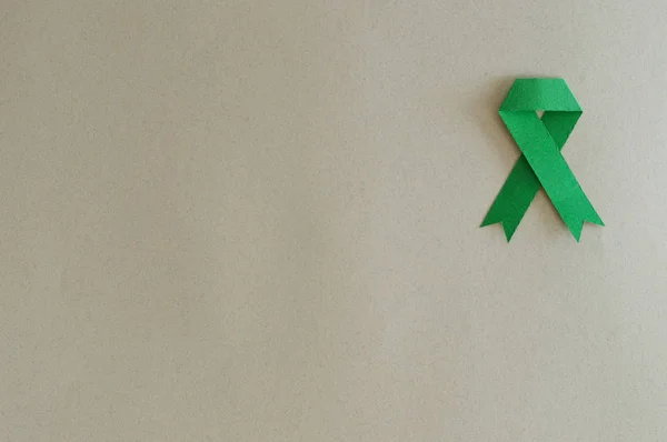 Liver cancer ribbon made with paper on beige background.