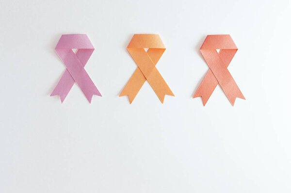 Trio of breast cancer uterus and leukemia ribbons made with paper on white background.