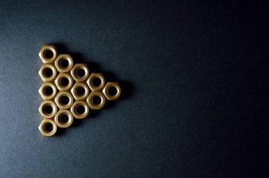 Koyu arka plan üzerinde şekiller oluşturan altın mekanik fındık