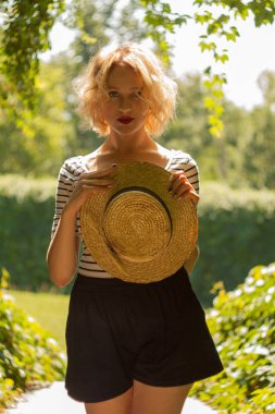 canotier şapka yeşil tünel tutarak ve kameraya bakarak kırmızı dudaklar genç kadınla