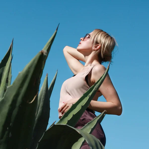 agav bitki önünde poz arkasında duran çekici genç kadın açık mavi gökyüzü ve seyir