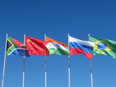 Mavi gökyüzüne karşı BRIC ülkelerinin bayrakları sallayarak. Brezilya, Rusya, Hindistan, Çin ve Güney Afrika Zirvesi