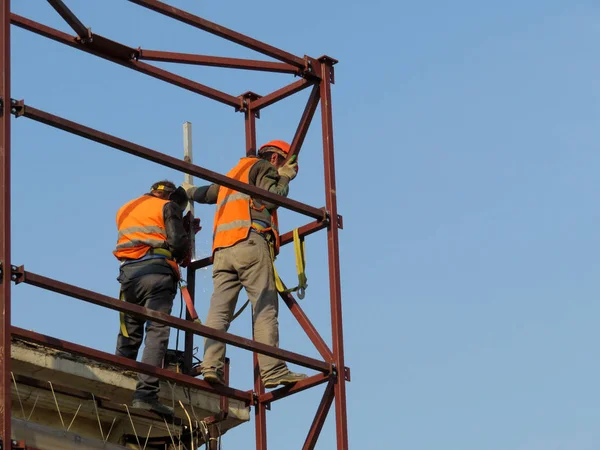 建設労働者が足場に作業します 澄んだ青い空を背景に建設現場で溶接工 — ストック写真