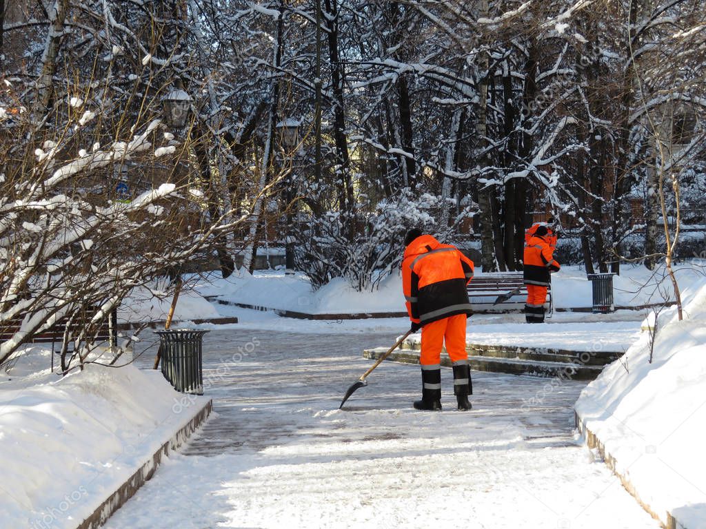 Snow removal. Communal services workers clear snow with a shovel, winter weather, street cleaning