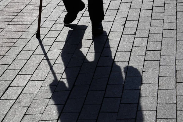 舗装の長い影 杖で歩く人のシルエット ラメや盲目の人 障害者 背骨の病気の概念 — ストック写真