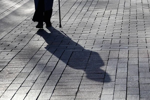 Silhouette and shadow of woman walking with a cane. Concept of blind person, limping, disability, old age, diseases of the spine, stranger