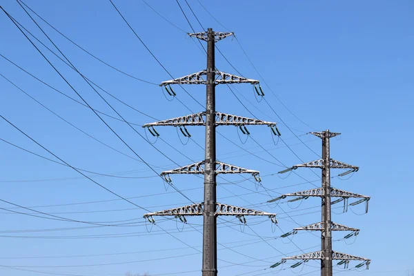High voltage power line supports with electrical wires isolated on clear blue sky background. Electricity transmission lines, power supply concept