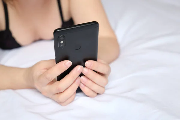 Kobieta Czarnej Bieliźnie Leżącej Łóżku Pomocą Smartfona Telefon Komórkowy Rękach — Zdjęcie stockowe