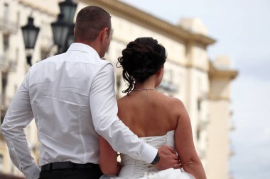 Bir şehirde düğün, damat gelinin bel kucaklar, arka görünümü. Sadece evli çift, yeni aile kavramı geleceğe bakıyor