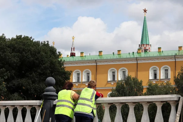 Moskova Kremlin'in arka planında süpürge saplan olan hademeler, yaz aylarında ortak işçi üniforması giyen iki kadın. Rusya'da emekçi göçmenler, sokak temizliği kavramı, çöp kaldırma, düşük ücretli