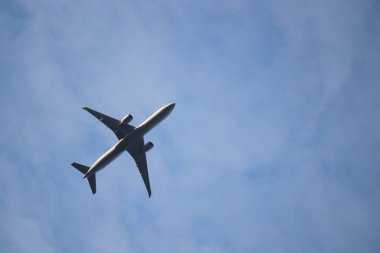 Mavi gökyüzünde uçan uçak, hava yolculuğu. Beyaz bulutların arka planında havalanıyor ticari çift motorlu uçağın silueti, türbülans konsepti