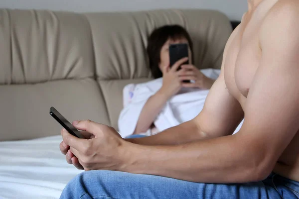 Couple using smartphones in a bed. Man and woman with mobile phones in bedroom, concept of family crisis, sexual and relationship issues, online addiction