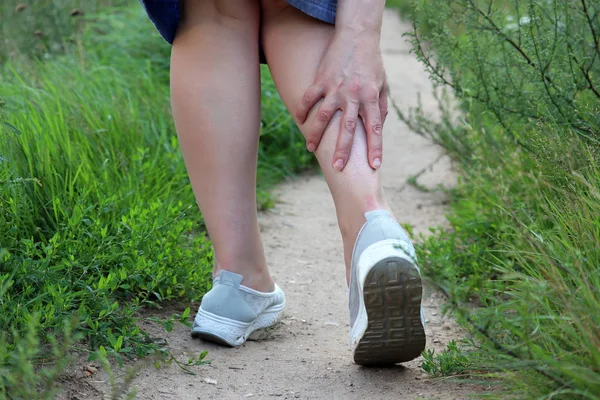 Ayak bileği Sprain, kadın bir yaz doğasında yürürken bacağını yakaladı. Yorgun bacaklarda ağrı kavramı, çalışan yaralanma