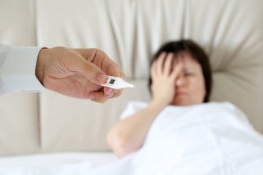 Yatakta yatan hasta kadın, erkek elinde dijital termometre. Hastanın vücut ısısını ölçen doktor, soğuk algınlığı ve grip kavramı, ateş, hastalık, baş ağrısı