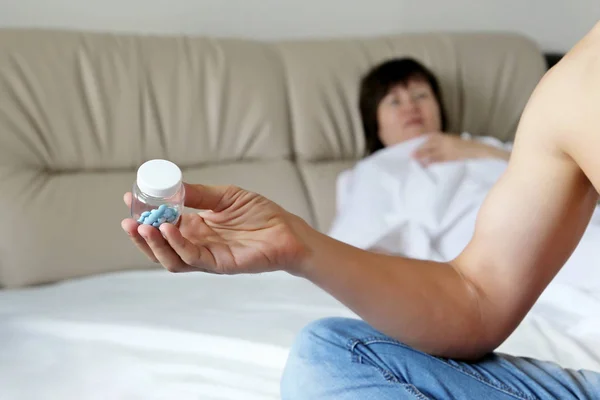 Seksten önce yatakta çift, adam ereksiyon için hap alır. Cinsel sorunlar kavramı, viagra, kontrasepsiyon, libido için ilaç