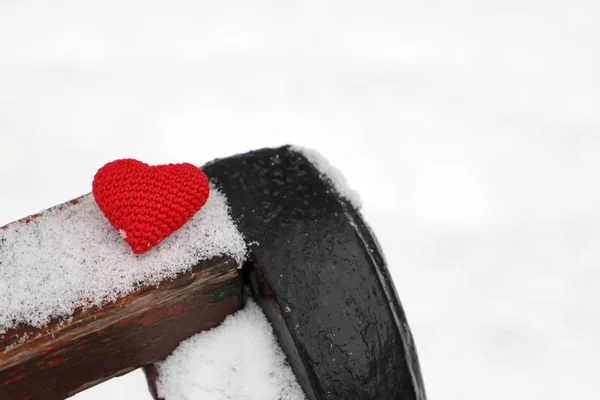 Love heart, Merry Christmas and winter card, red knitted symbol of love in the snow on a bench. Concept of romance, New Year celebration, Valentine\'s day or snowy weather