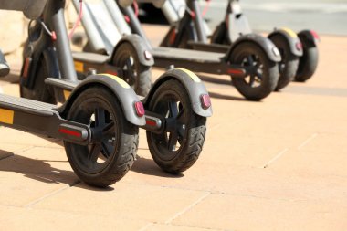 Elektrikli scooter güneşli bir günde bir sokakta park etti. Şehir içi ulaşım kiralama sistemi, otoparkta e-scooter