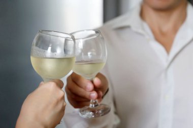 Romantik bir randevuda beyaz şarap içen bir çift. Sisli şarap bardakları, düğün kavramı, kutlama, aşk tarihi tarafından beyaz gömlek klink kadın ve adam