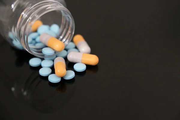 Şişedeki haplar, koyu cam masadaki kapsüllerde ilaç. Eczacılık kavramı, antibiyotikler, vitaminler