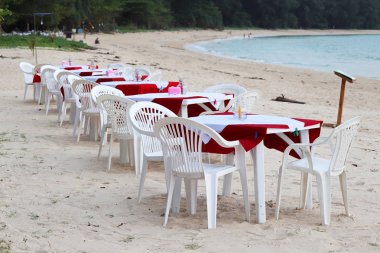 Plaj kafesi, deniz kenarında açık bir restoranda masa örtüleri olan boş plastik masalar. Phuket, Tayland 'da boş zaman ve tarih belirleniyor
