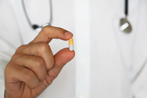Doktor hapları tutuyor, erkek eli kapsülün kapsülünde. Tabletli adam, eczacı, ilaç, diyet hapı, antidepresan veya vitamin konsepti
