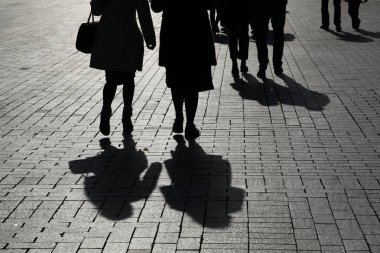 Siyah siluetler ve sokaktaki insanların gölgeleri. Kaldırımda yürüyen kalabalık, yayalar, toplum ve şehir hayatı kavramı.
