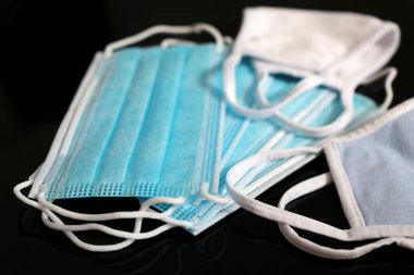 Medical masks on black glass background. Different type protection from coronavirus infection