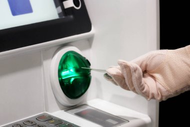 Kadın ATM alıcısına bir banka kartı yerleştiriyor. Korumacı bir eldiven, mali işlem ve güvenlik önlemleri içinde kadın eli covid-19 koronavirüs salgını sırasında