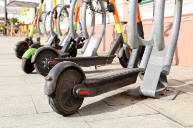 Otoparkta arka arkaya elektrikli scooterlar. Şehir bisiklet kiralama sistemi, sokakta elektronik scooterlar.