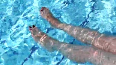 Kadın bacaklarını şeffaf bir yüzme havuzunda sallıyor. Pedikür, ayak bakımı, tatil, sağlık ve spa konsepti olan mükemmel kadın bacakları.