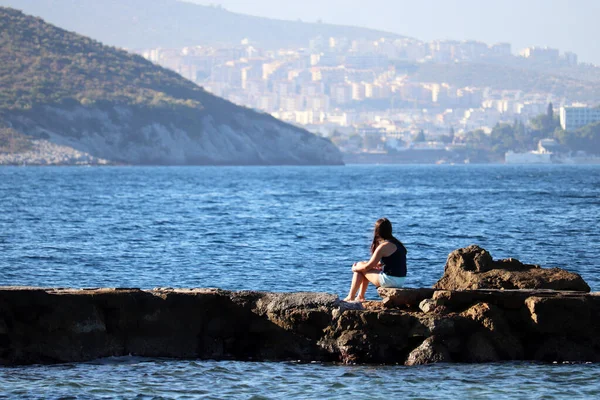 Meisje Korte Broek Zittend Rotsen Bergen Zee Dorpsachtergrond Strand Vakantie — Stockfoto