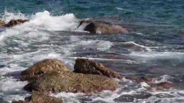 Deniz dalgaları deniz kıyısındaki tehlikeli kayalara çarpıyor. Taşlardaki temiz köpüklü su, okyanus fırtınası.