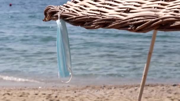 Medicinsk Ansiktsmask Hängande Korgparasoll Blå Hav Bakgrund Säkerhet Strand Coronaviruspandemi — Stockvideo