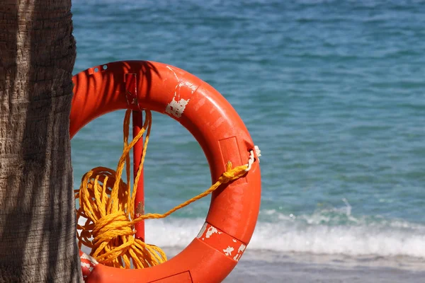 Orange lifebuoy on a beach. Safety on a water, life ring on blue sea background