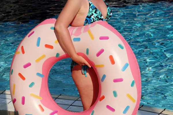 Yüzme havuzunun yanında şişme donut yüzüğü takan bikinili bir kadın. Plaj tatili, rahatlama ve rahatlama konsepti.
