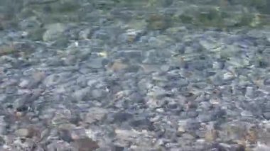 Yumuşak dalgalı berrak deniz suyu, çakıl tabanlı şeffaf yüzey. Stone Beach, doğal arka plan.