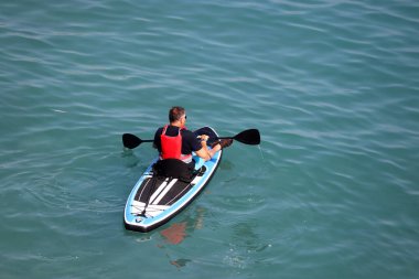 Nup sörfü, elinde kürekle deniz suyunda sörf yapan bir adam. Ayakta kürek çekme, üst görünüm