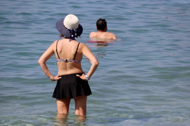 Sırtında ben olan, deniz suyunda dikiz aynasından bakan mayo giymiş bir kadın. Plaj tatili, dinlenme ve rahatlama.